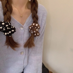 Close-up of black and brown polka dot hair scrunchies worn on a braided hairstyle