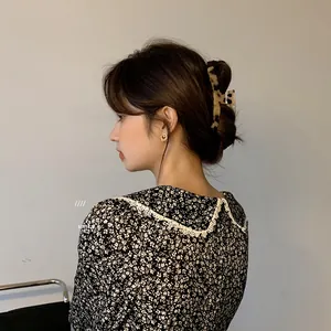 Detail of leopard print hair claw clip and gold heart earring on elegant model