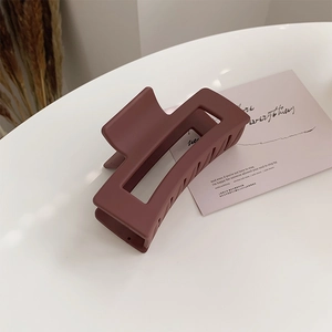 Detailed macro view of large matte rectangular hair claw clip in deep mahogany finish
