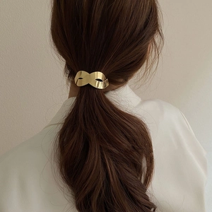Pince à queue de cheval en métal doré torsadé sur cheveux bruns pour un style élégant