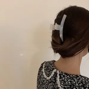 Elegant large pearlescent hair claw clip shown in a low bun hairstyle for women