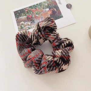 Detail of red and grey houndstooth plush scrunchie with soft knitted fabric texture