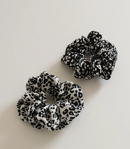 Detail view of two leopard print scrunchies in classic black and white chiffon fabric