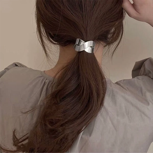 Détail d'un élastique à cheveux en métal argenté torsadé sur de longs cheveux bruns