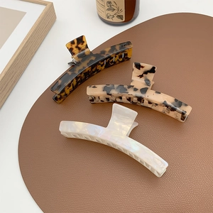 Three elegant acetate hair claws in tortoiseshell, leopard print, and pearl white colors