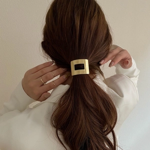 Vue détaillée d'un bijou de queue de cheval carré doré de style minimaliste chic