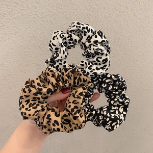 Detailed close-up of three leopard print scrunchies in brown, beige, and monochrome styles