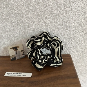 Detailed view of large zebra striped scrunchie with soft fabric texture and pleated design