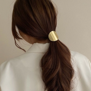 Accessoire élastique doré minimaliste sur une queue de cheval pour un look pro
