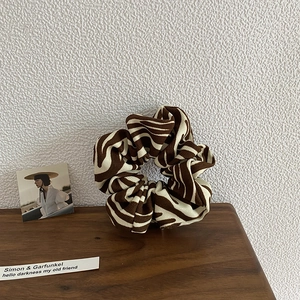 Detailed close-up of large zebra print scrunchie on a wooden surface with soft lighting