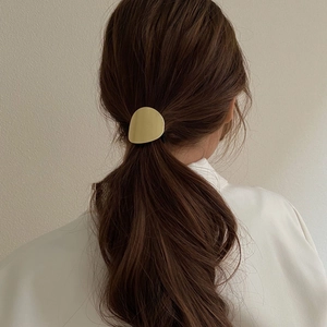 Détail de l'élastique à cheveux doré en métal sur une queue de cheval brune