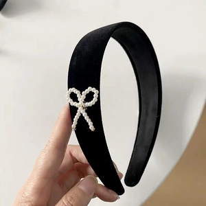 Detailed close-up of a vintage black velvet headband featuring an elegant pearl bow design