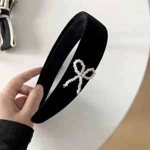 Detailed close-up of a vintage black velvet headband featuring a pearl bow decoration