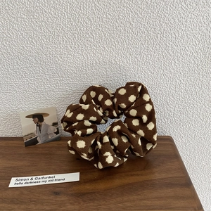 Close-up of a brown polka dot oversized scrunchie with soft ribbed fabric texture