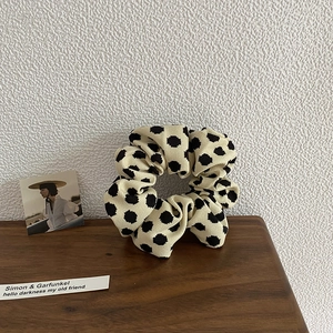 Detailed shot of beige polka dot scrunchie with soft ribbed fabric and natural pleats