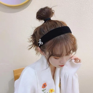 Vintage black velvet headband with pearl bow detail worn by a model in a cozy setting