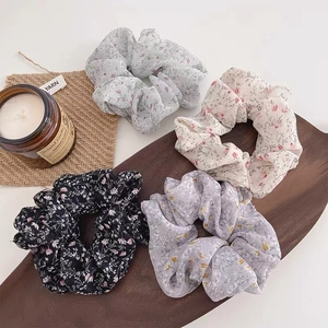 Close-up of floral scrunchies in blue, pink, black, and purple on a wood tray