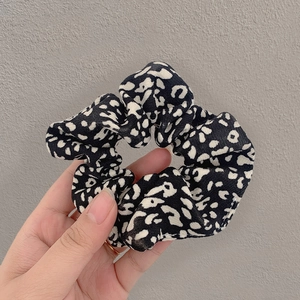 Detail shot of leopard print fabric scrunchie with layered pleats held in hand