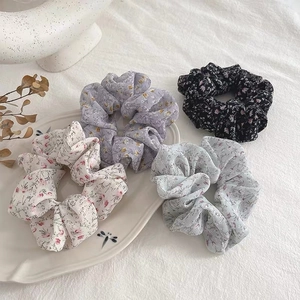 Detailed view of four floral pattern scrunchies displayed on an elegant ceramic plate