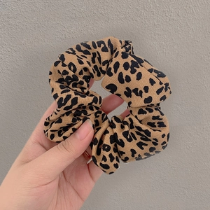 Close-up of a leopard print scrunchie made of elastic fabric held in hand