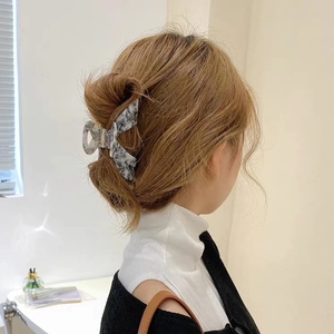 Detail of large acetate hair claw with marble ink pattern holding a full hair bun