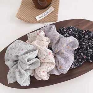 Floral print scrunchies set in four colors displayed on a rustic wooden tray