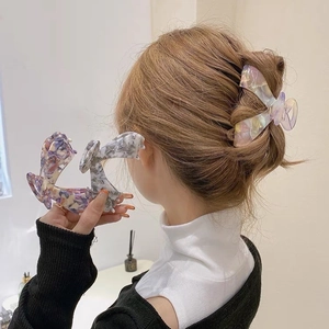Detail of colorful marble acetate hair claw clips with ergonomic bow-shaped design