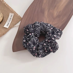 Detail of dark floral scrunchie on a wooden tray in a natural home lifestyle setting