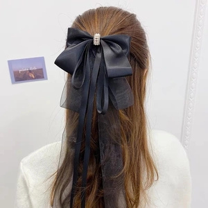 Pince à cheveux nceud noir avec longs glands en maille et perles sur cheveux bruns