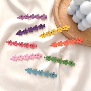 Set aus acht bunten matten Haarspangen in Blumenform auf weißem Seidenstoff