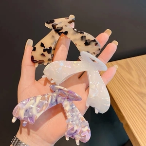 Three large acetate hair claws in leopard, pearl white, and purple marble patterns
