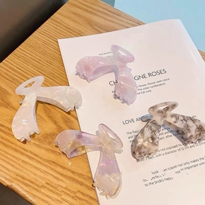 Close-up of four large acetate hair claws in various marble colors on a wooden table