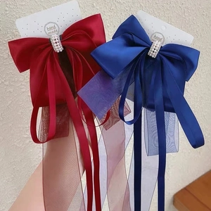 Détail de nœuds à cheveux en satin avec perles et rubans en organza rouge et bleu
