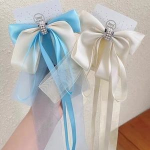 Détail de la pince à cheveux nœud en satin bleu et blanc avec organza et perles
