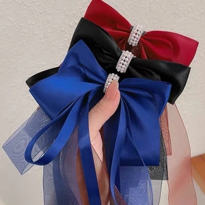 Détail de barrettes à nœuds avec rubans en satin et perles centrales en trois couleurs