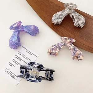 Detailed close-up of large acetate hair claws in marble patterns with sturdy metal springs