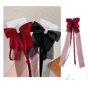 Détail de la barrette à nœud en satin avec perles et longs rubans en bordeaux et noir élégant