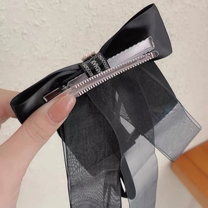 Détail de la pince à cheveux noeud noir avec rubans longs en satin et organza