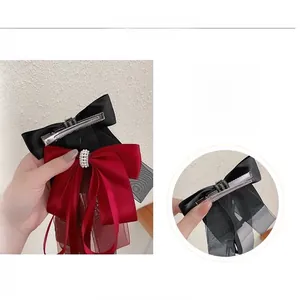 Détail de nœuds à cheveux en satin rouge et noir avec rubans en tulle et perles