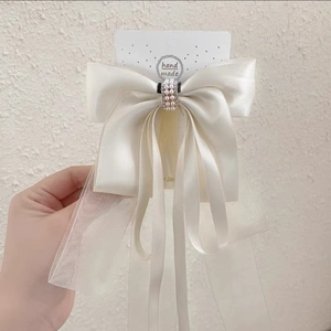 Détail de la pince à cheveux nœud crème avec couches de satin et perles fantaisie