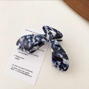 Detail view of large marble texture acetate hair claw clip with elegant blue and white patterns