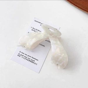 Detail of elegant large cream acetate hair claw clip with pearlescent marble texture