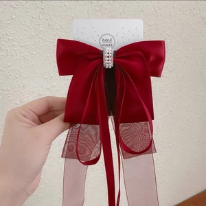 Détail de la barrette nœud en soie rouge avec perles blanches et longs rubans en organza