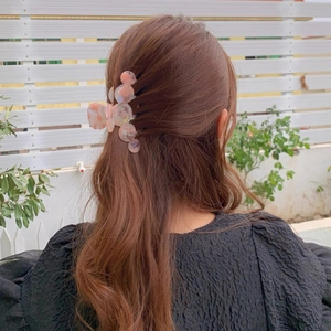 Detail of a floral acetate hair claw clip with pink and orange marble patterns in hair