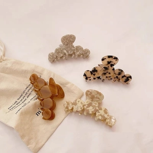 Set of four French acetate hair claws in tortoise shell and marble patterns with a linen pouch
