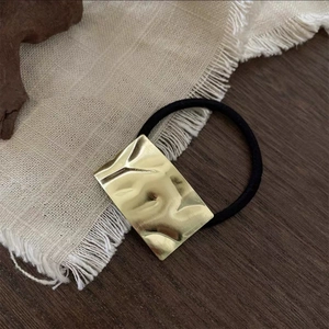 Black high-elastic hair tie featuring a golden pleated-texture metal rectangle accent