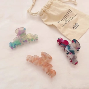 Three large acetate hair claws in marble green, pink gradient, and multicolor patches