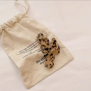 Detailed view of a French acetate leopard print hair claw clip on a linen pouch