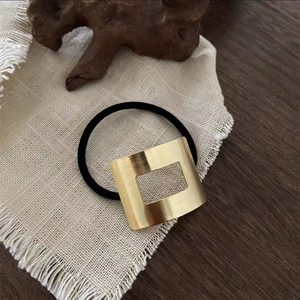 Golden brushed square metal hair ring with black elastic band in minimalist style