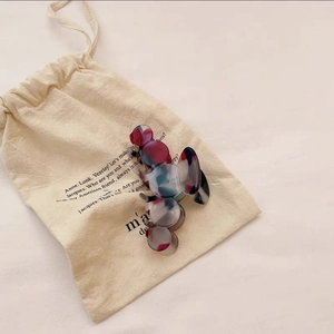 Detail of elegant acetate hair claw clip with marble pattern on a cotton pouch